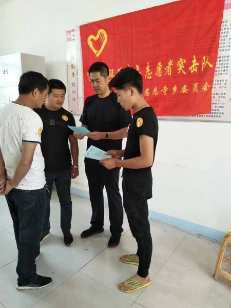 齊剛(右二)正帶領(lǐng)著村青年志愿者突擊隊(duì)一起研究改善村容村貌的措施