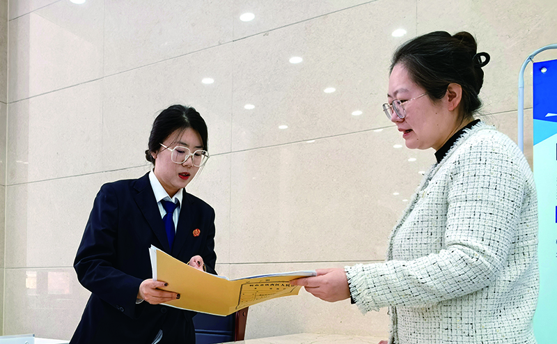 訴服中心的涉企案件綠色通道窗口,法官助理張嘉鑫正耐心指導(dǎo)當(dāng)事人填寫訴答文書